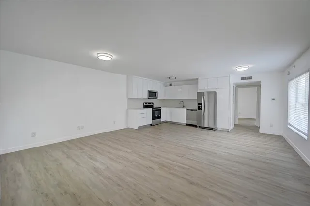 a view of empty room with kitchen and window