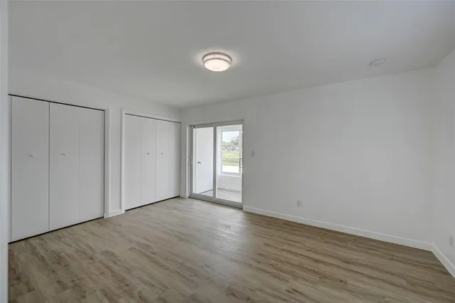 a view of an empty room with wooden floor and window