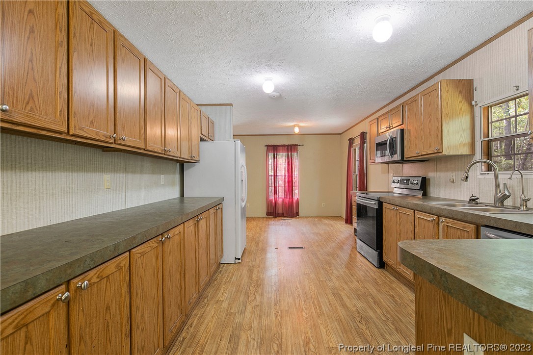 4759 Darroch Road Lillington, NC 27546 - Photo 15 of 50 a kitchen with stainless steel appliances granite countertop a sink a stove cabinets wooden floor and black chairs