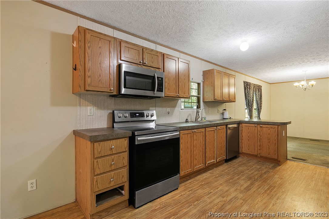 4759 Darroch Road Lillington, NC 27546 - Photo 17 of 50 a kitchen with stainless steel appliances granite countertop a stove top oven a sink dishwasher and wooden cabinets with wooden floor
