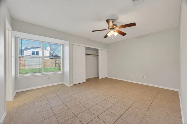 a view of an empty room with cabinet and a ceiling fan