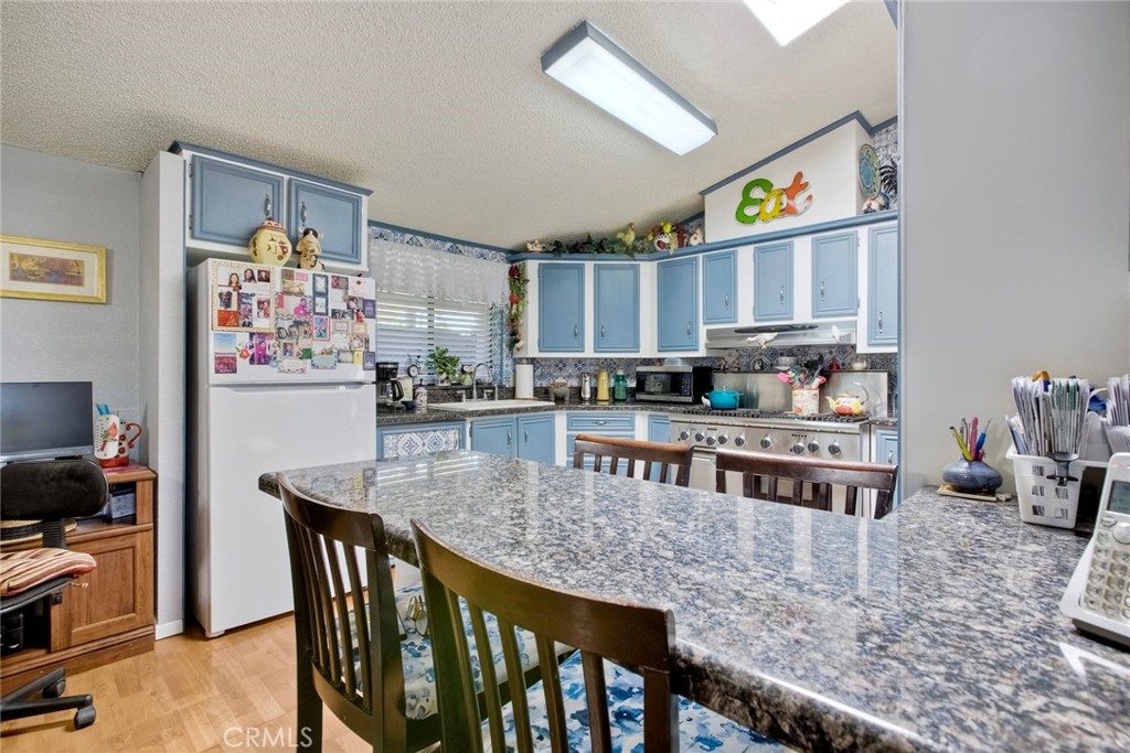 34370 The Farm Road Wildomar, CA 92595 - Photo 18 of 31 a kitchen with stainless steel appliances granite countertop a stove top oven a sink a dining table and chairs with wooden floor