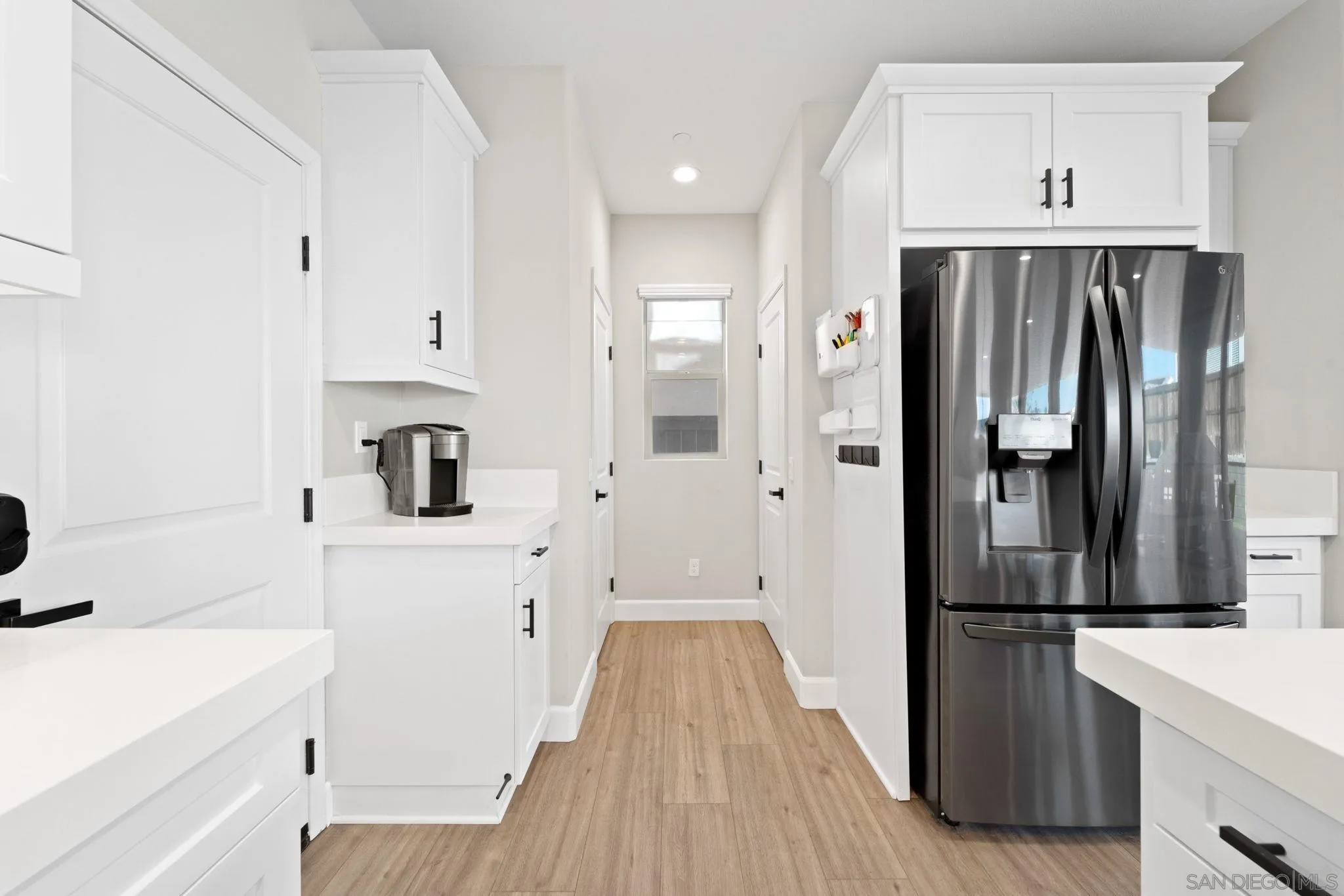 1279 Camino Prado Chula Vista, CA 91913 - Photo 10 of 38 a kitchen with a refrigerator and white cabinets