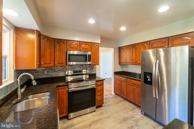 a kitchen with stainless steel appliances granite countertop a stove a sink and a refrigerator