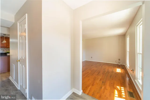 a view of a hallway with wooden floor and a bathroom