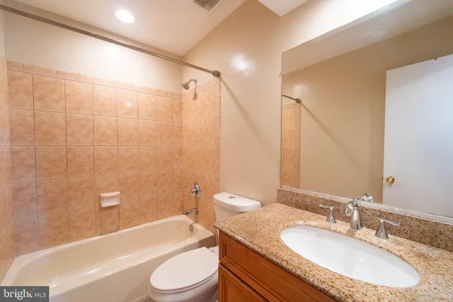 a bathroom with a granite countertop sink toilet tub and shower