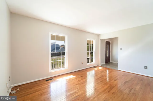 a view of an empty room with wooden floor and windows