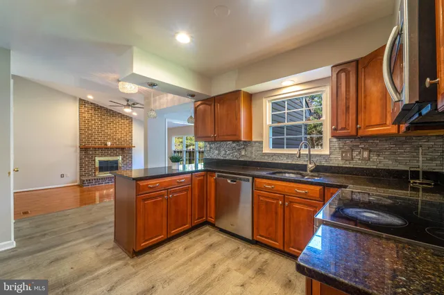 a kitchen with stainless steel appliances granite countertop wooden cabinets a stove a sink and a large window