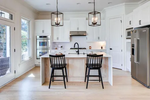 a view of kitchen with stainless steel appliances granite countertop a dining table chairs refrigerator and sink