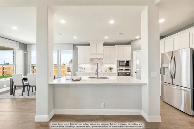 a kitchen with kitchen island stainless steel appliances a sink a stove a refrigerator and cabinets