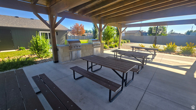 1500 Angel Street North, Unit 53 Layton, UT 84041 - Photo 19 of 20 Covered outdoor patio with exposed beam pergola, dual built-in gas grills, stone-finish counter space, and multiple picnic tables