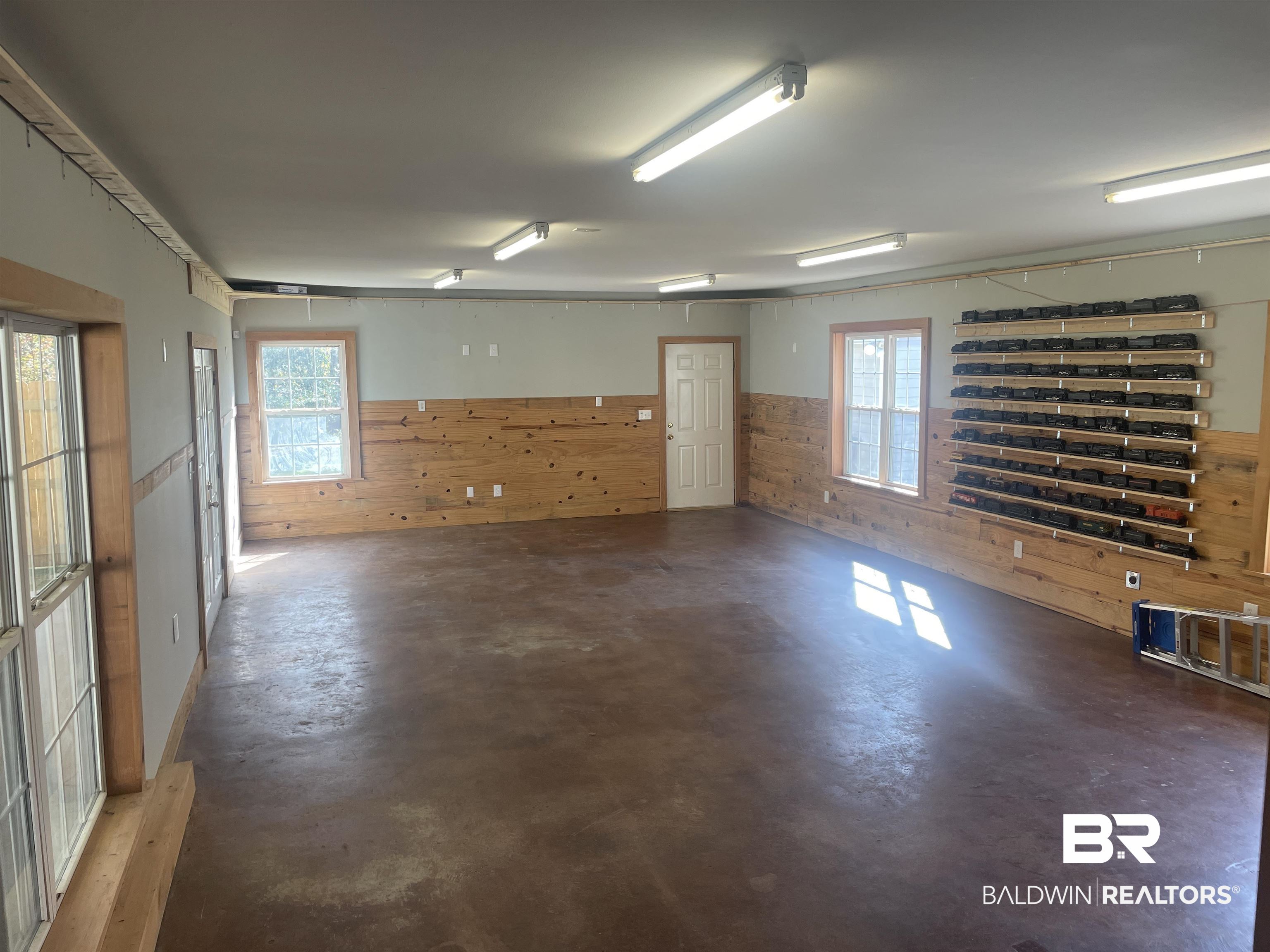13850 Celeste Road Chunchula, AL 36521 - Photo 17 of 29 Empty room featuring finished concrete flooring, wood walls, and a wainscoted wall