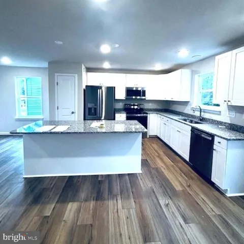a large kitchen with wooden floors and stainless steel appliances
