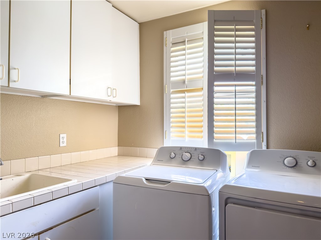 1842 Bogey Way Henderson, NV 89074 - Photo 12 of 25 Laundry area with a textured wall, cabinet space, and washing machine and clothes dryer
