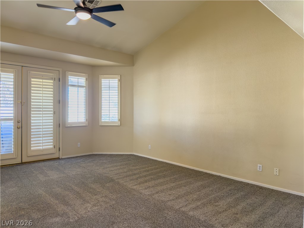 1842 Bogey Way Henderson, NV 89074 - Photo 15 of 25 Empty room featuring vaulted ceiling, dark carpet, a ceiling fan, and french doors