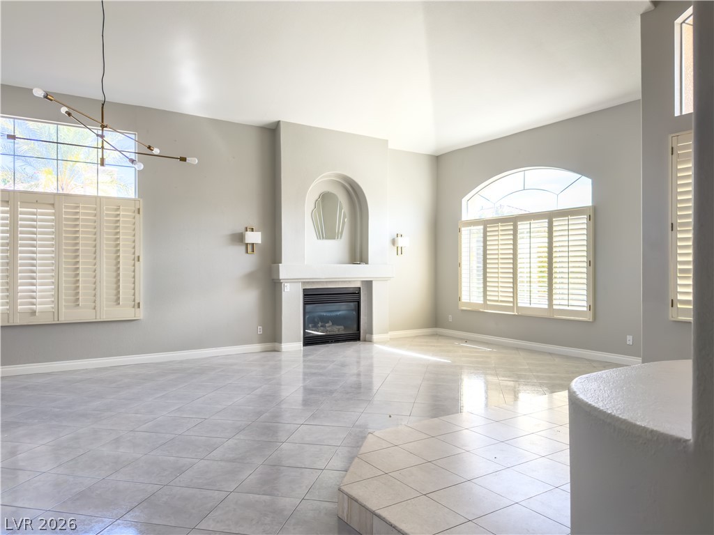 1842 Bogey Way Henderson, NV 89074 - Photo 20 of 25 Unfurnished living room with plenty of natural light, light tile patterned floors, a glass covered fireplace, and hanging lights