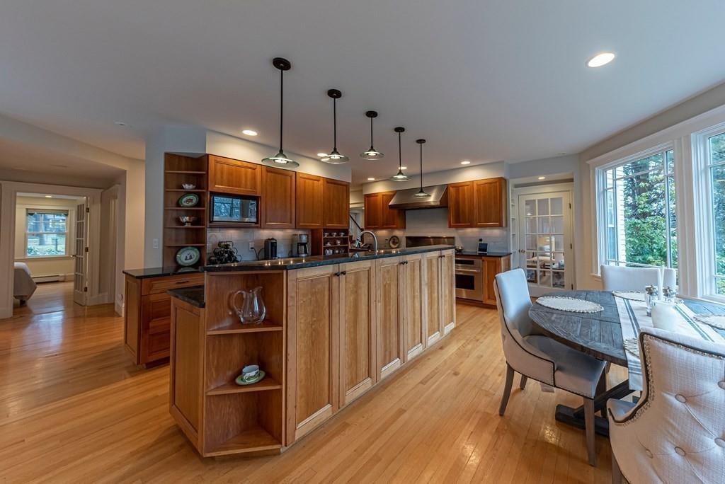 9 Blake Road Lexington, MA 02420 - Photo 17 of 41 a open kitchen with stainless steel appliances kitchen island granite countertop a refrigerator a stove a sink a dining table and chairs with wooden floor