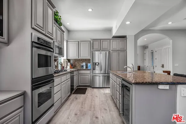 a kitchen with stainless steel appliances granite countertop a kitchen island hardwood floor sink stove and granite counter top