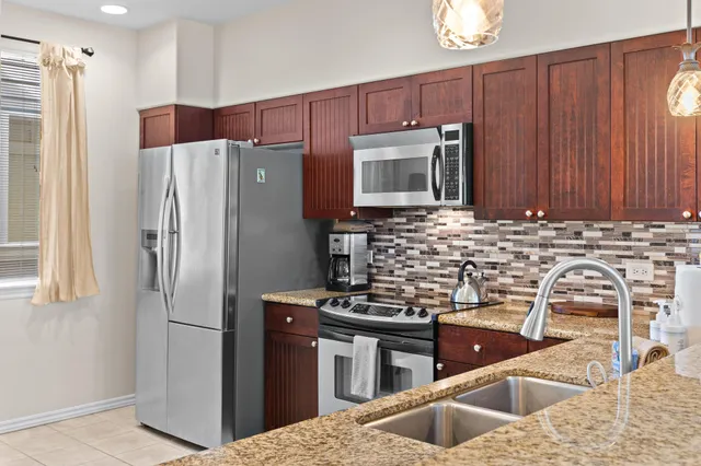 a kitchen with stainless steel appliances granite countertop a refrigerator a stove a sink and dishwasher