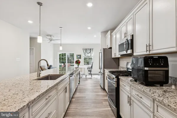 a kitchen with stainless steel appliances granite countertop a sink a stove top oven a counter space and cabinets