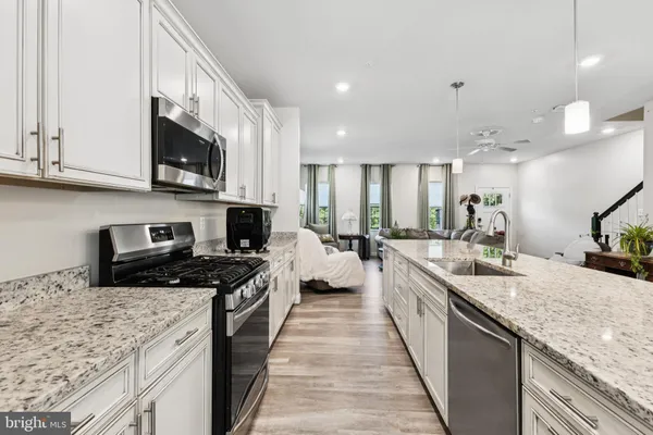 a large kitchen with stainless steel appliances granite countertop a stove top oven a sink dishwasher and a microwave