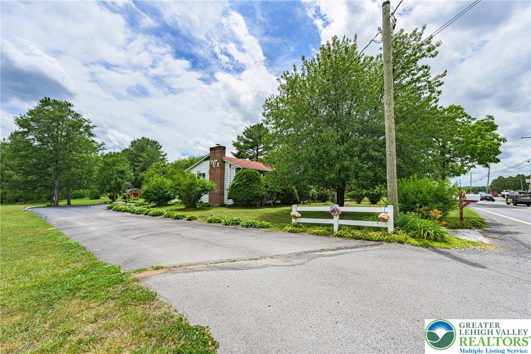 678 Interchange Road Kresgeville, PA 18333 - Photo 37 of 45 A winding asphalt driveway leads to a charming residence, surrounded by mature trees and lush green landscaping.