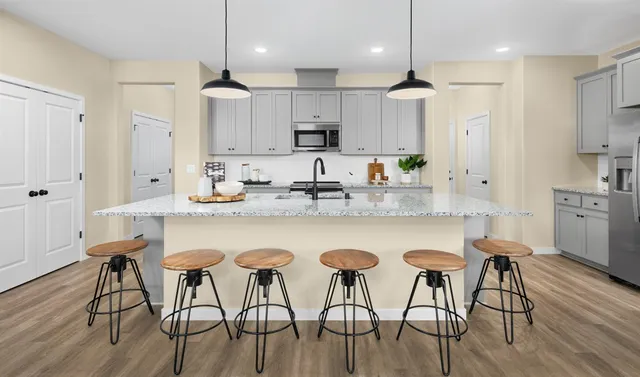 a kitchen with stainless steel appliances granite countertop a dining table chairs stove refrigerator and cabinets