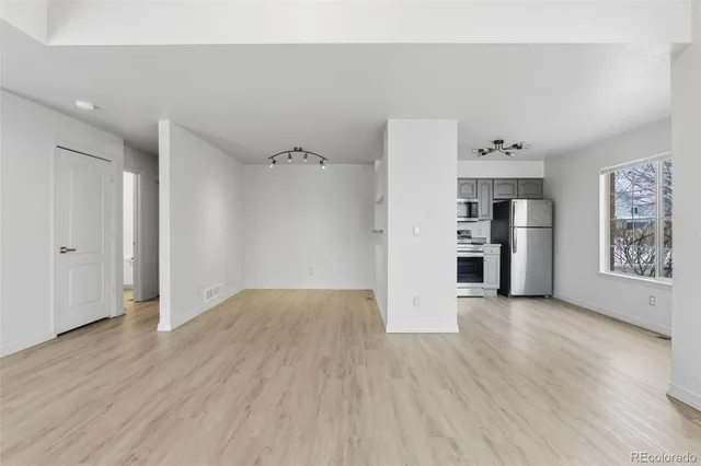 an empty room with wooden floor closet and windows