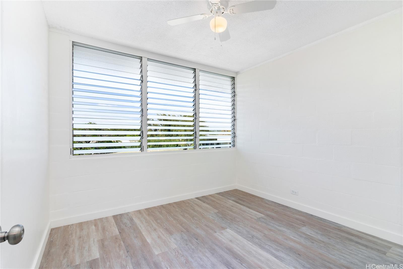 94-249 Waikele Road, Unit A307 Waipahu, HI 96797 - Photo 7 of 20 an empty room with wooden floor and windows