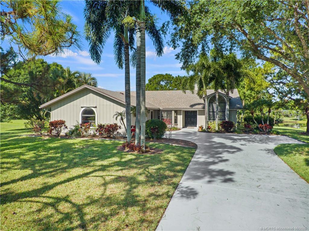 5692 Southeast Lamay Drive Stuart, FL 34997 - Photo 1 of 28 a front view of a house with a garden and trees