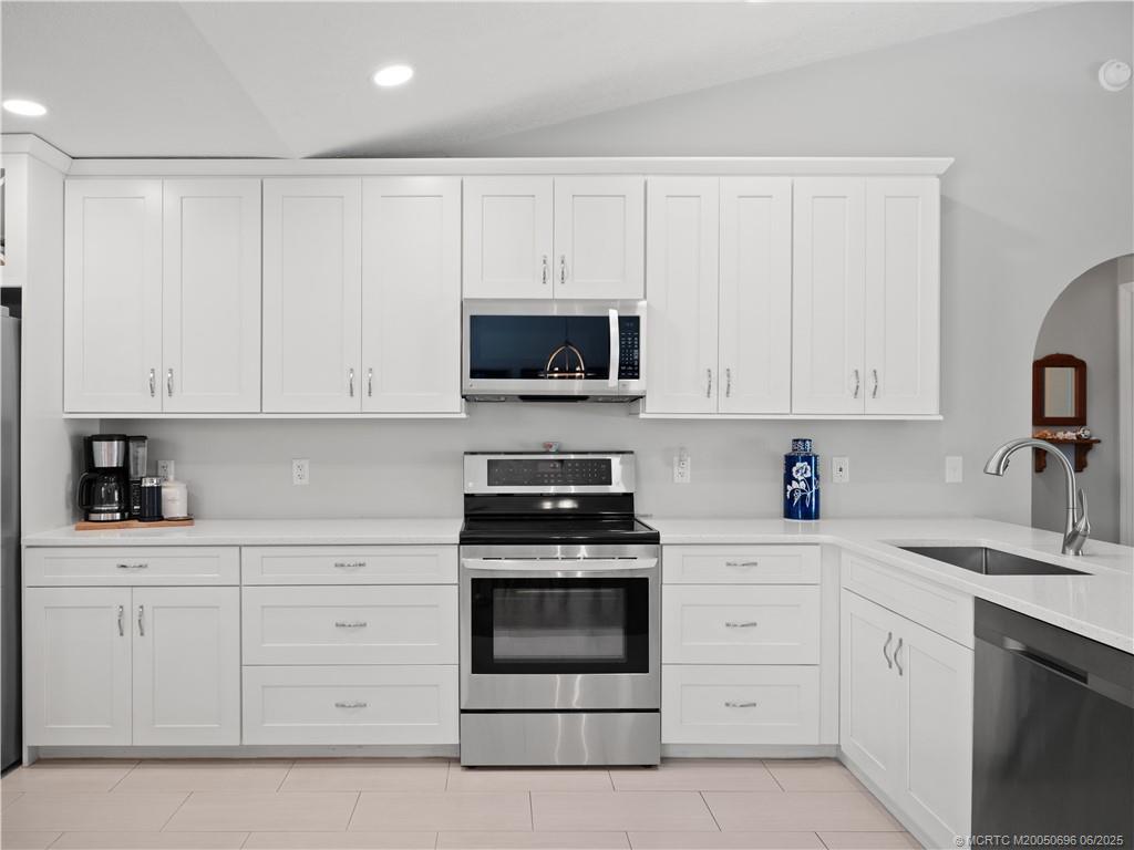 5692 Southeast Lamay Drive Stuart, FL 34997 - Photo 11 of 28 a kitchen with white cabinets and stainless steel appliances