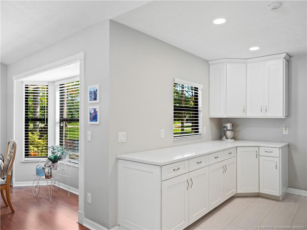 5692 Southeast Lamay Drive Stuart, FL 34997 - Photo 12 of 28 a kitchen with white cabinets and wooden floor