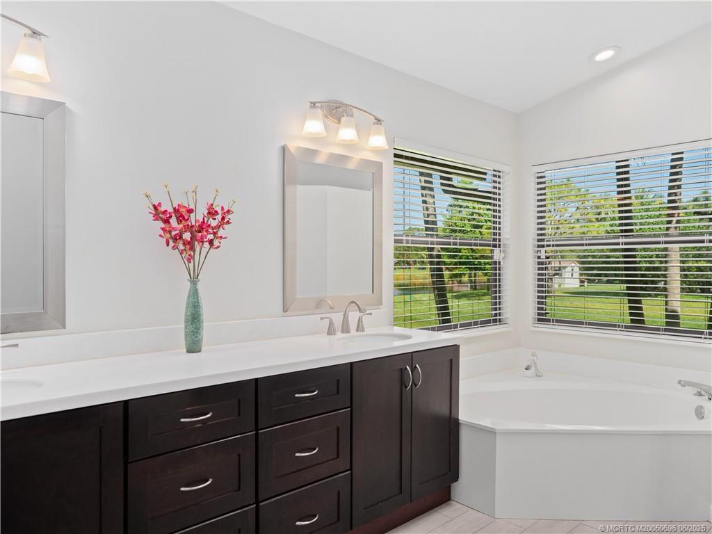 5692 Southeast Lamay Drive Stuart, FL 34997 - Photo 17 of 28 a bathroom with a tub sink and mirror