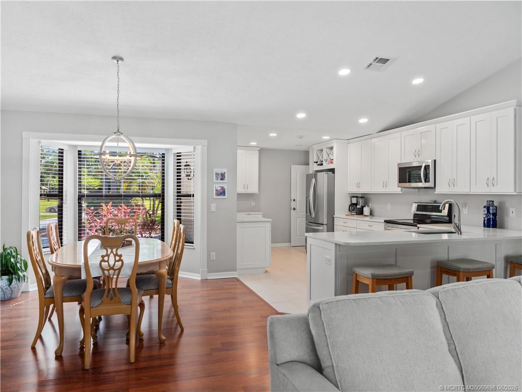 5692 Southeast Lamay Drive Stuart, FL 34997 - Photo 7 of 28 a view of a dining room and livingroom with furniture wooden floor kitchen chandelier