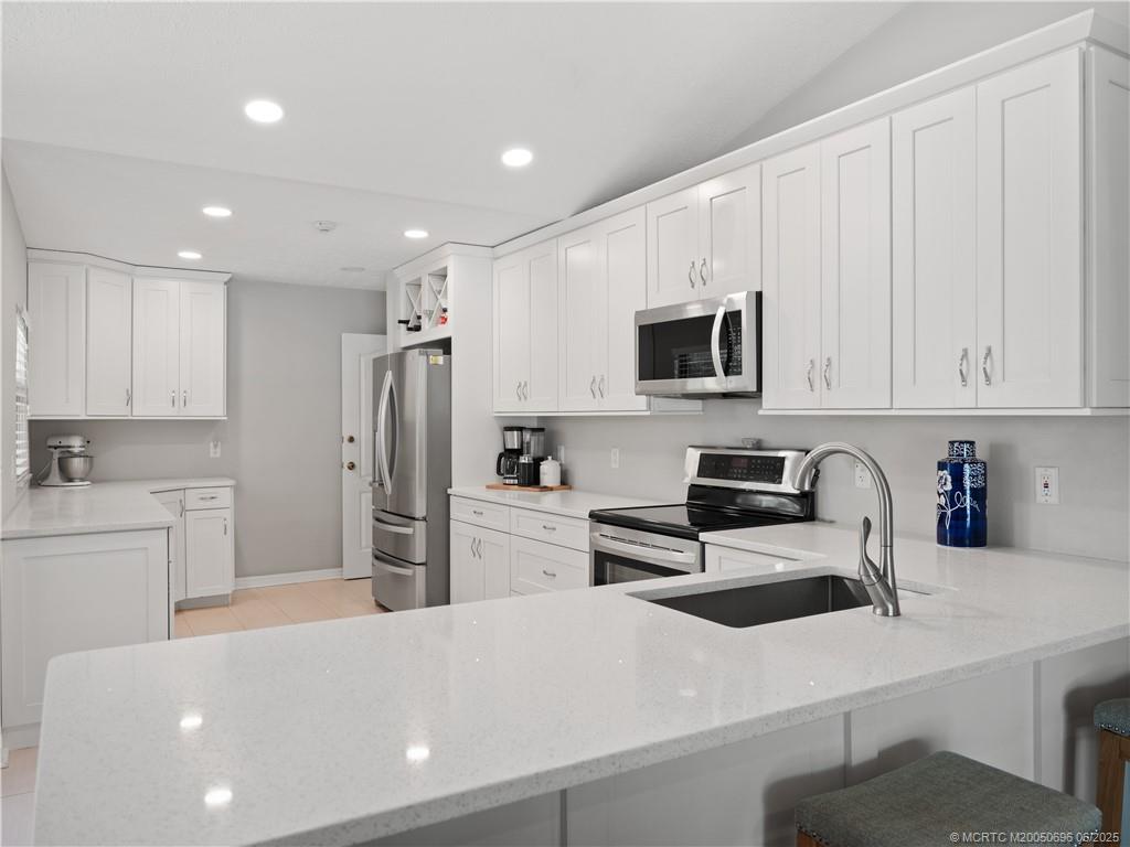5692 Southeast Lamay Drive Stuart, FL 34997 - Photo 9 of 28 a kitchen with stainless steel appliances a refrigerator sink and white cabinets