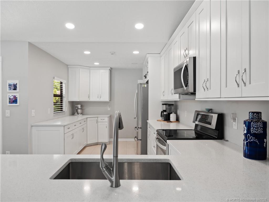 5692 Southeast Lamay Drive Stuart, FL 34997 - Photo 10 of 28 a kitchen with stainless steel appliances kitchen island granite countertop a sink a stove and cabinets