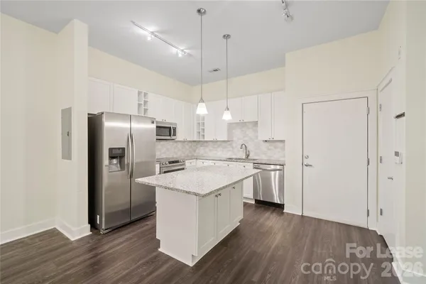 a kitchen with a refrigerator a sink and wooden floor
