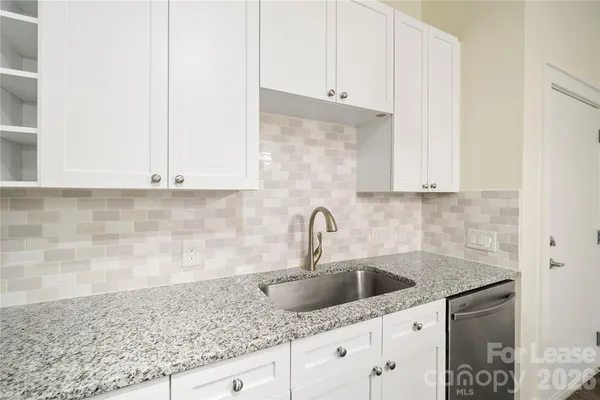 a kitchen with granite countertop white cabinets and a sink
