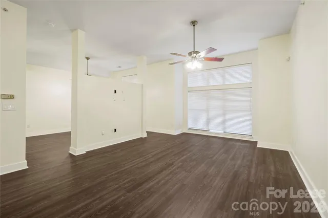 an empty room with wooden floor and ceiling fan
