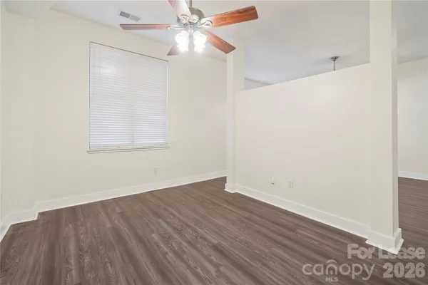 an empty room with wooden floor fan and windows