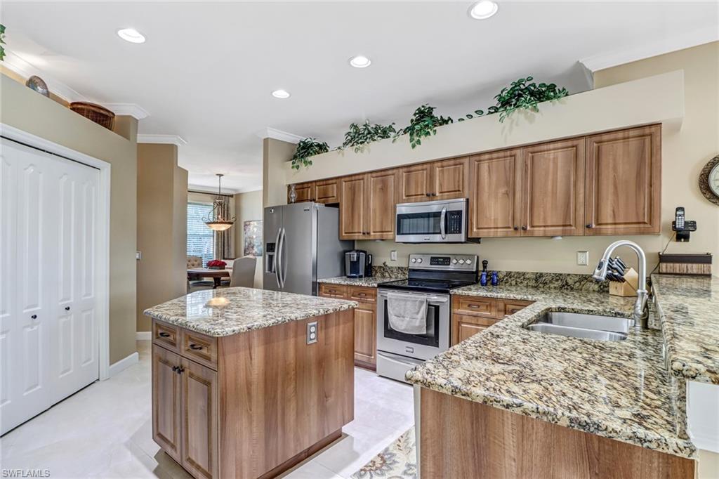 21156 Braxfield Loop Estero, FL 33928 - Photo 12 of 43 a kitchen with stainless steel appliances granite countertop a stove top oven a sink dishwasher and a refrigerator with wooden floor