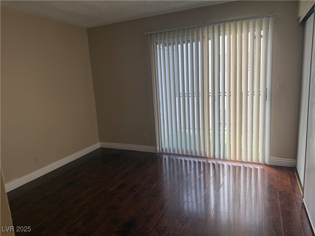 4689 West Sand Creek Avenue, Unit C Las Vegas, NV 89103 - Photo 10 of 14 Unfurnished room featuring a textured ceiling and dark wood-type flooring