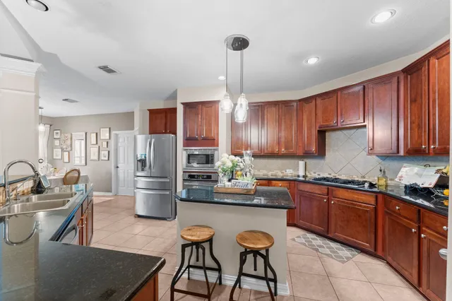 a kitchen with refrigerator a sink and chairs