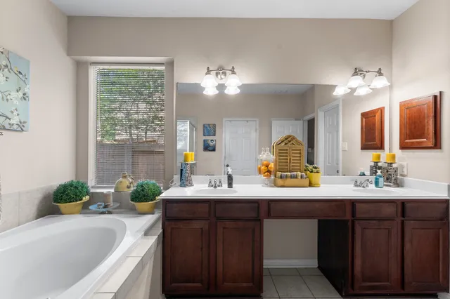 a bathroom with a tub a sink double vanity and a mirror