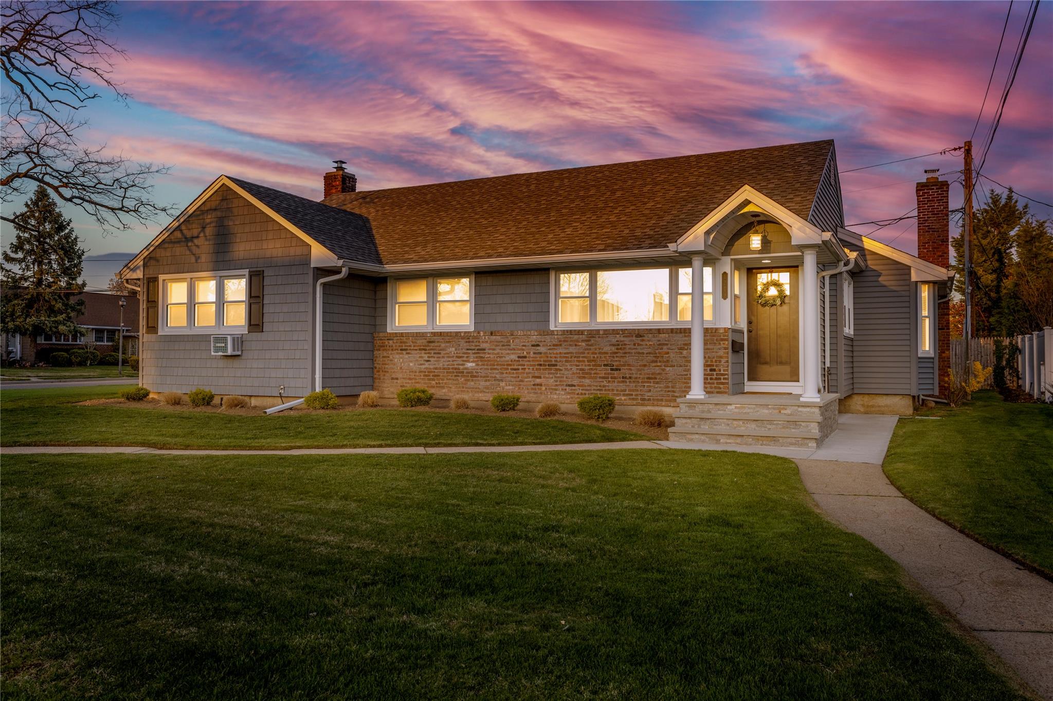 View of front of house with roof with shingles, a chimney, and a front lawn