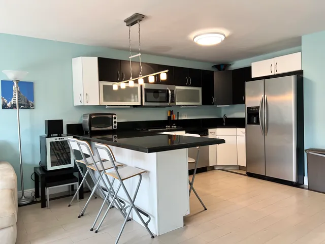 a kitchen with a sink a refrigerator and chairs