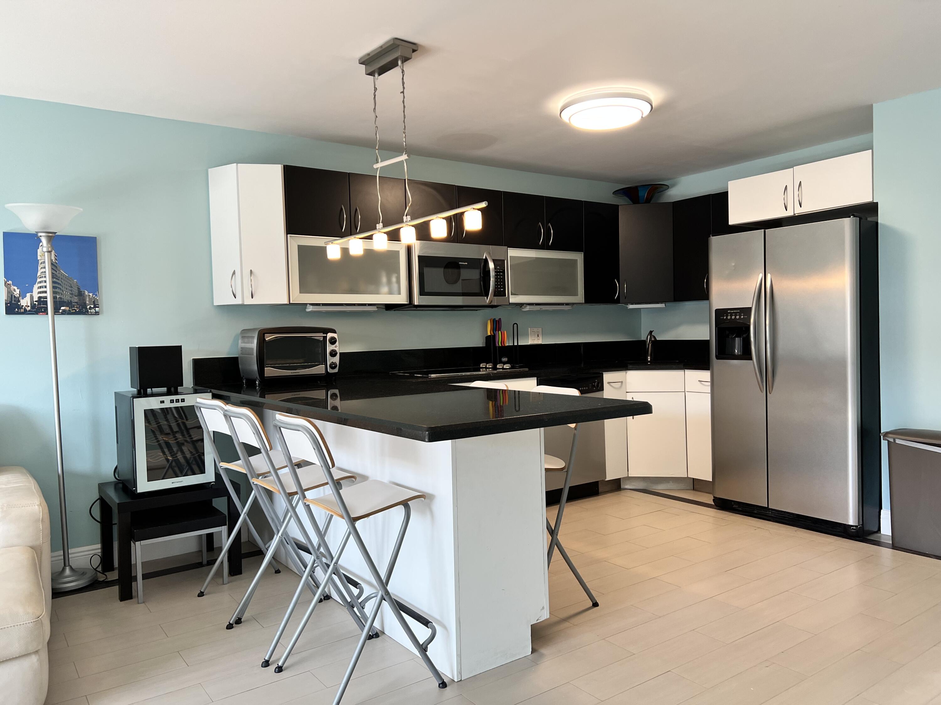 2029 North Ocean Boulevard, Unit 510 Fort Lauderdale, FL 33305 - Photo 10 of 39 a kitchen with a sink a refrigerator and chairs