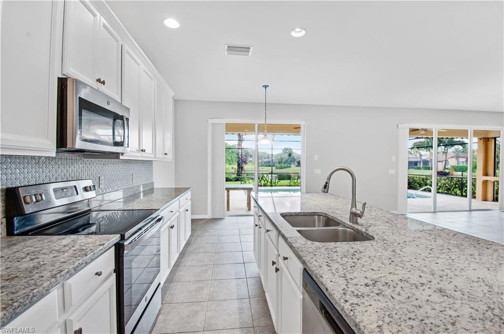 2133 Fairmont Lane Naples, FL 34120 - Photo 4 of 31 a kitchen with stainless steel appliances granite countertop a sink dishwasher a stove a microwave oven with granite countertops and cabinets