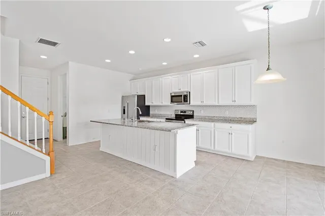 a kitchen with stainless steel appliances kitchen island granite countertop a stove a sink and a refrigerator