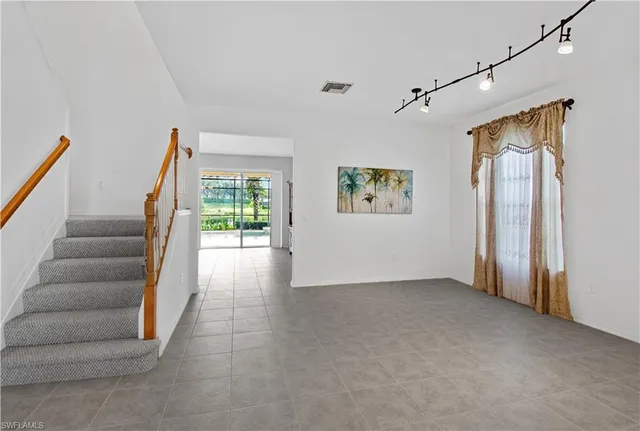 a view of an empty room with stairs and a window